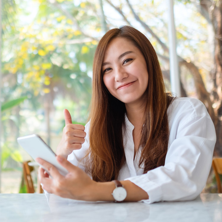 woman on phone smiling giving a thumbs up